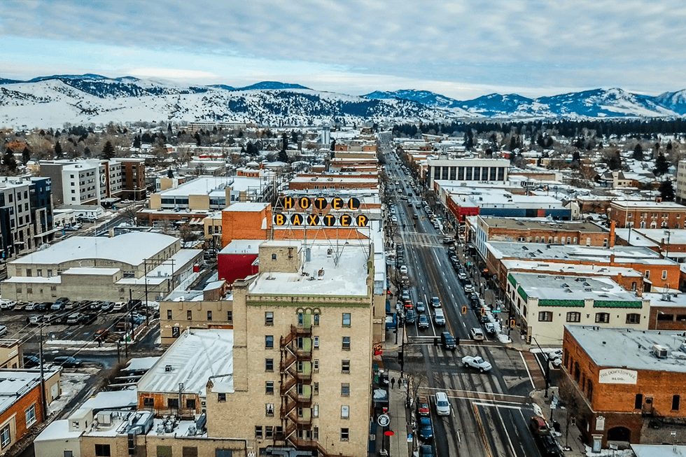 Aerial View of Main Street in downtown Bozeman Montana. Winter snow is scattered on streets and buildings with the mountain range covered in snow in the distance