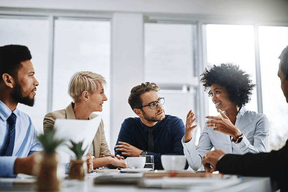 Three coworkers discussing plans written on a glass dry erase board